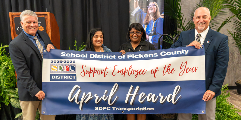 April Heard, standing with Support Employee of the Year banner