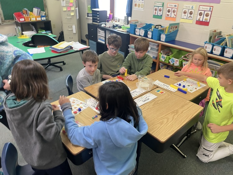 first and fifth grade students playing a math game. 