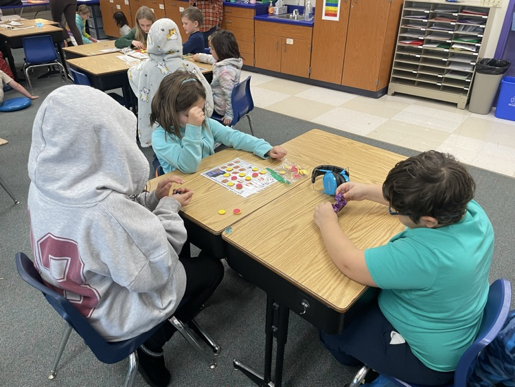 first and fifth grade students playing a math game. 