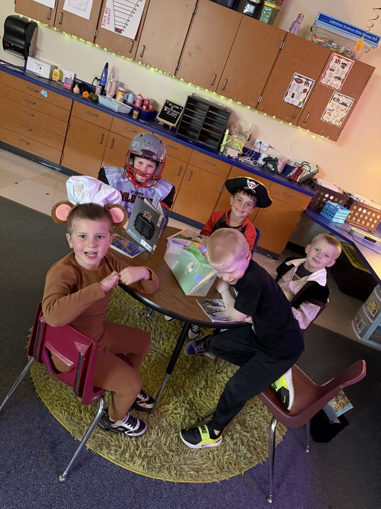 first graders reading together at a table in costumes