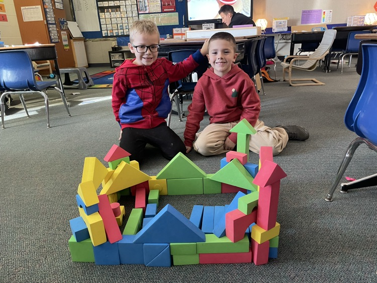 two boys building a castle out of foam blocks