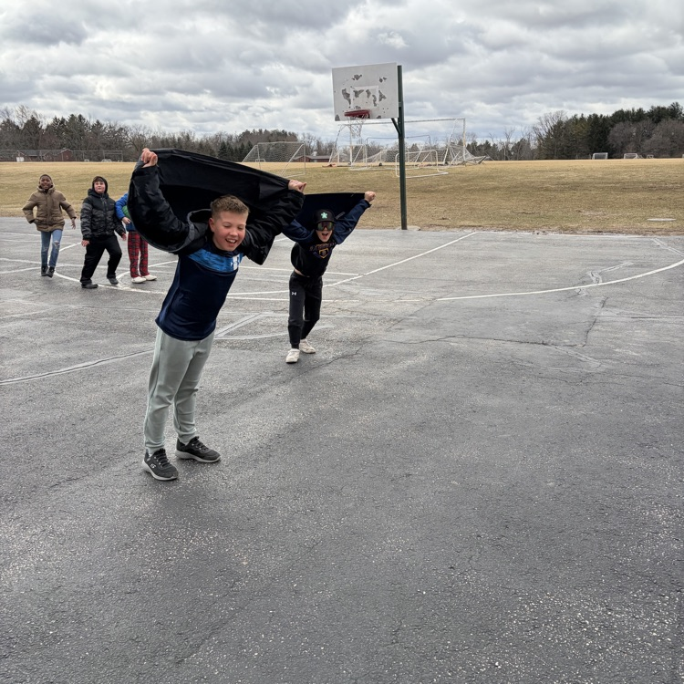 child outside pretending to fly with their coat