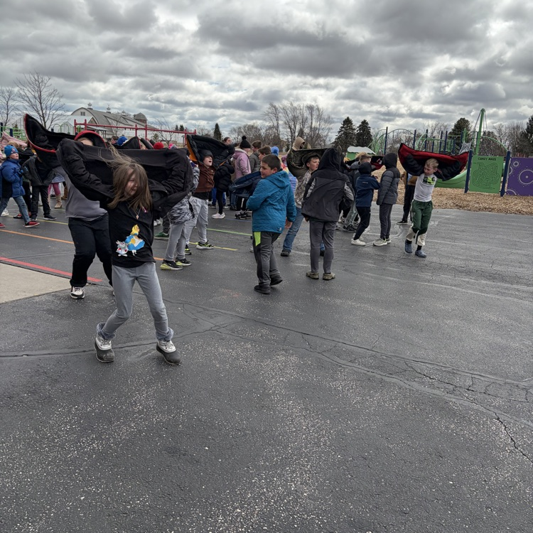 child outside pretending to fly with their coat