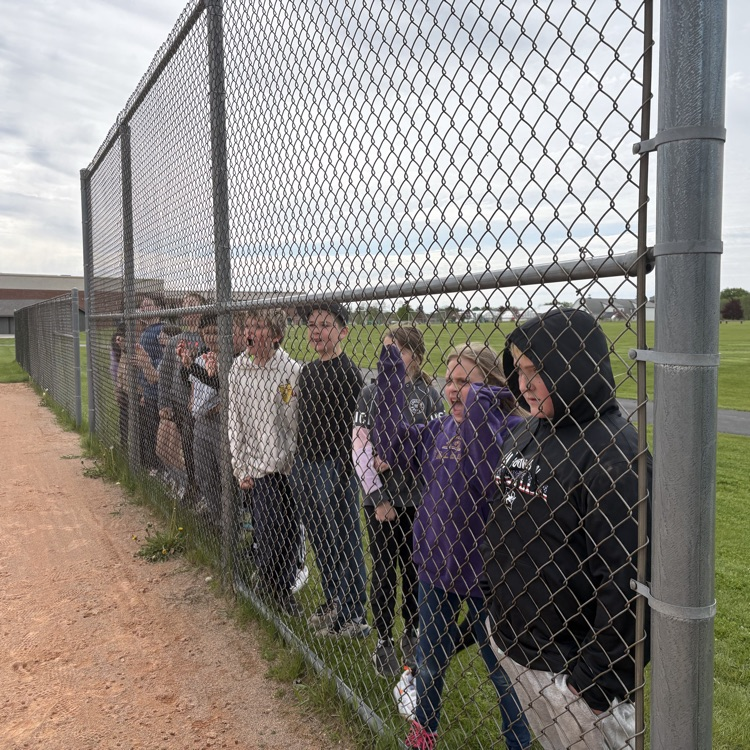 students standing along fence waiting for their turn to kick