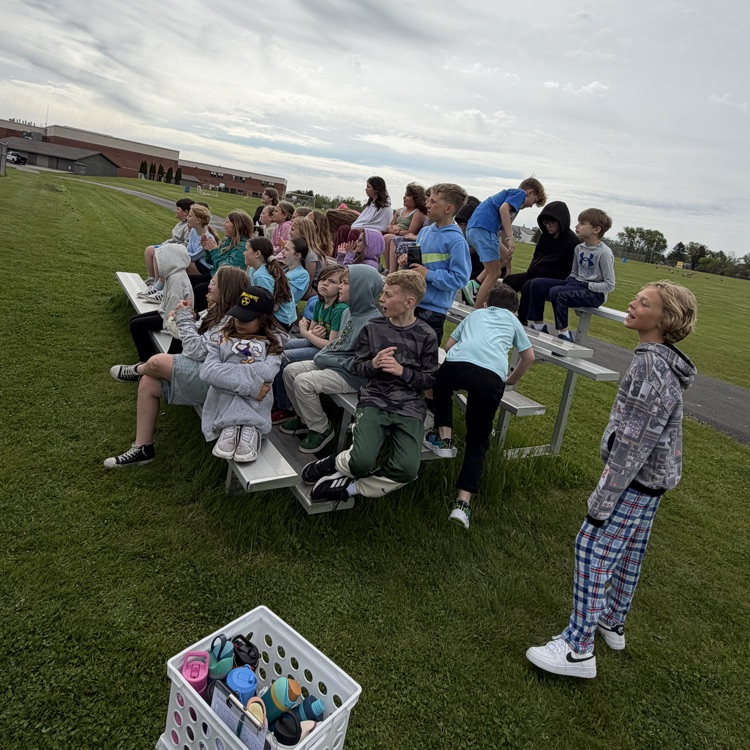 students sitting on bleachers watching a kickball game