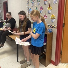 students reading from a paper to class of students