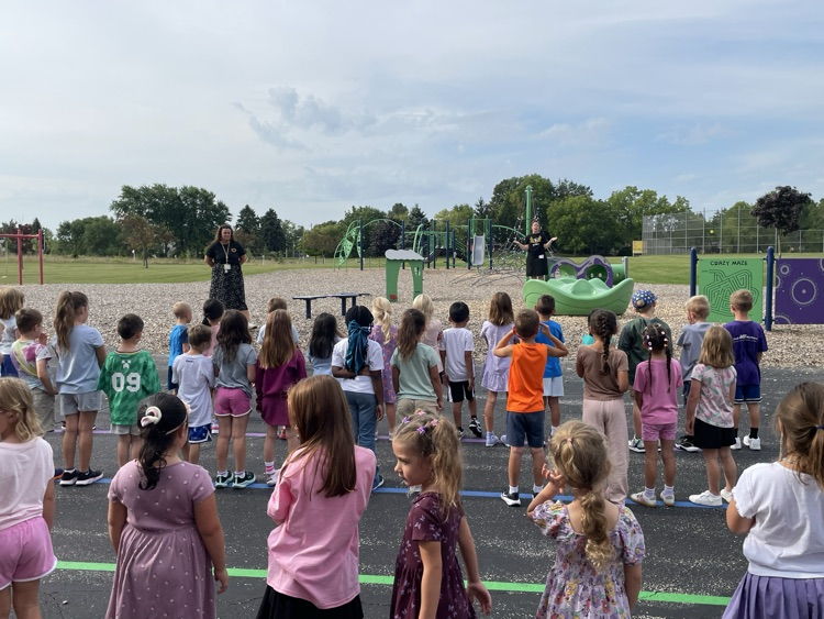 Students listening to a teacher on the playground. 