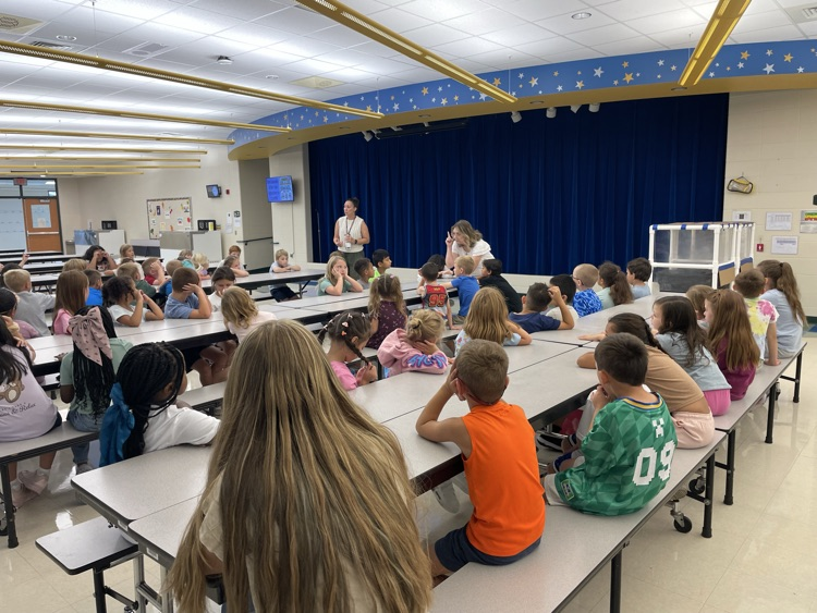 Students listening to school counselors learning about cafeteria rules. 