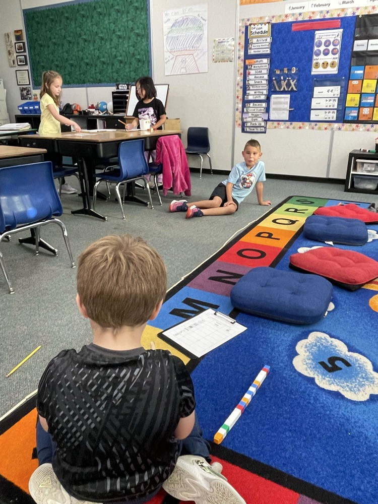 a group of 1st graders measuring with popsicle sticks. 