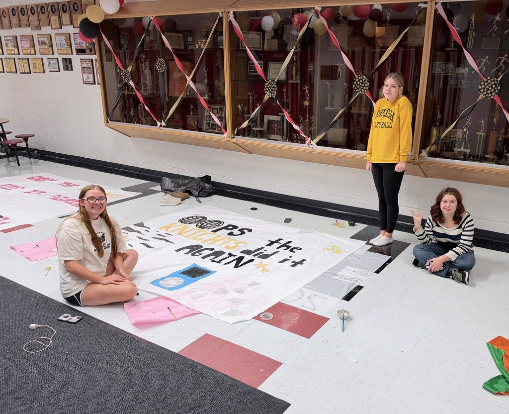 Three people work on a banner on a floor with colorful tiles.