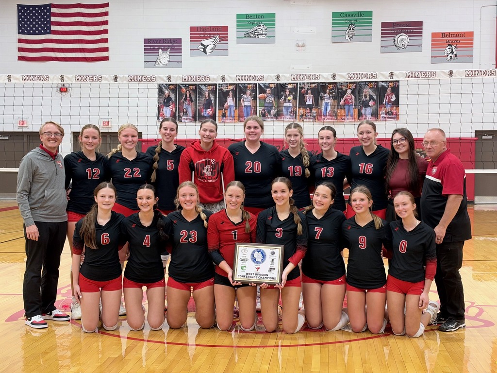 Team wearing red, black, and white jerseys pose with a trophy on a basketball court.