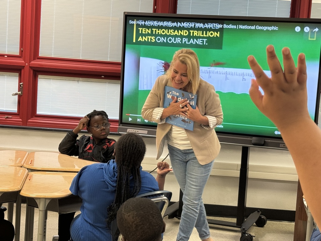 Teacher smiling holding the book that she read to students in a classroom