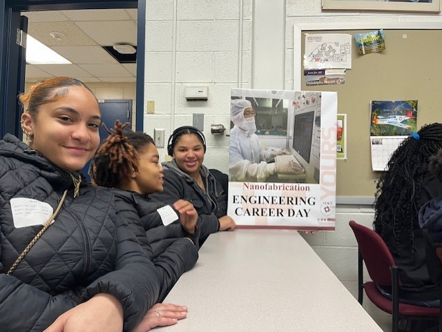 A group of students smiling and holding up a sign