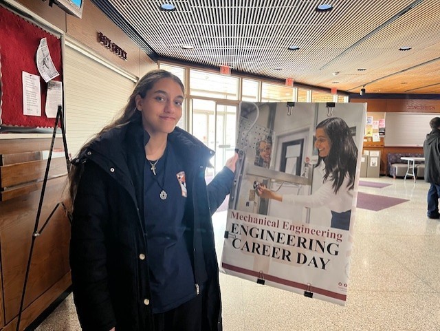 A student smiling and holding up a sign 