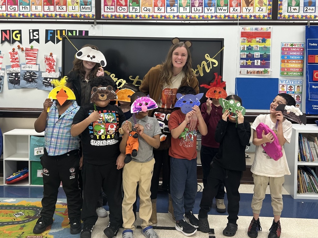 Group of students and adult smiling and holding up masks