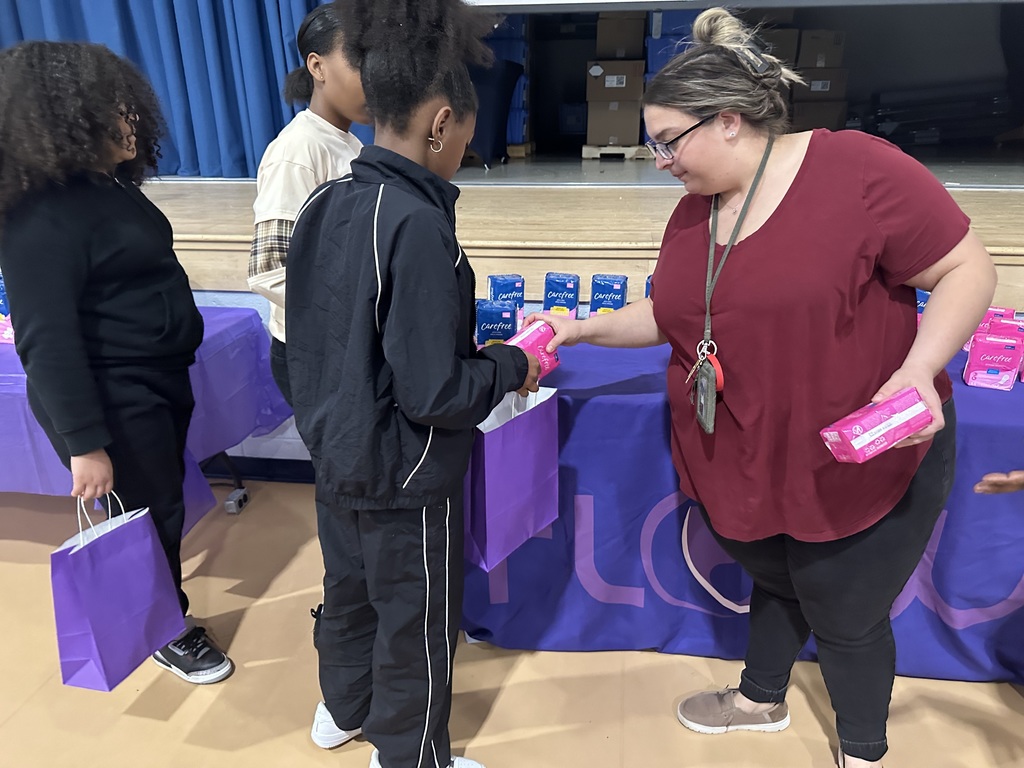 An adult putting a product in a student's bag