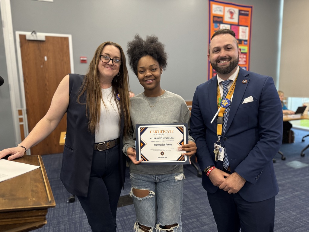 Goode Principal, Dr. Kelly Koerner with Goode Assistant Principal, Brandon Shiposh presenting a student from Goode with the Celebrating Families Award during a School Board Committee Meeting.