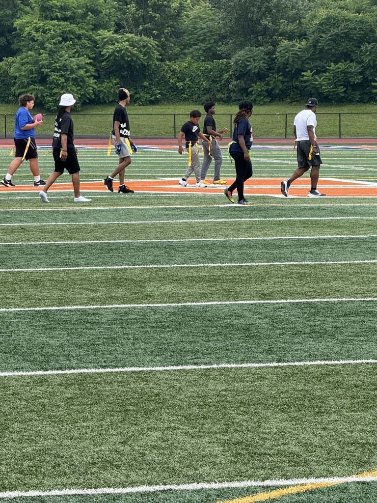 Seven people walking in a line playing flag football on a field