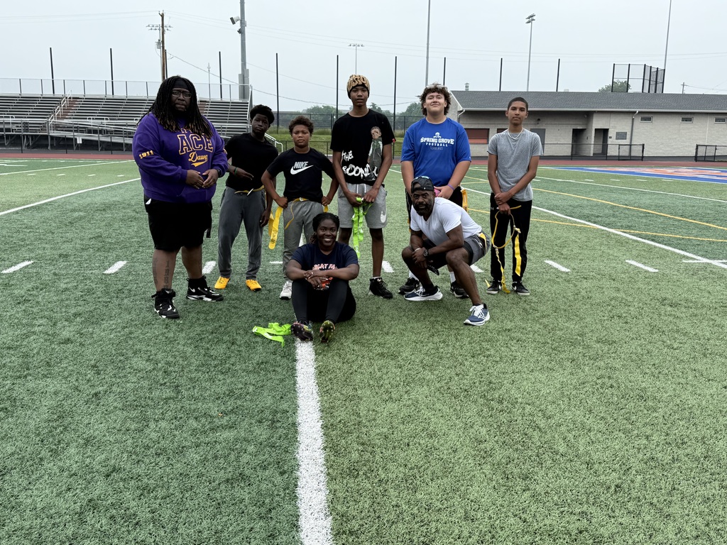 Group of nine people posing for a photo on a sports field