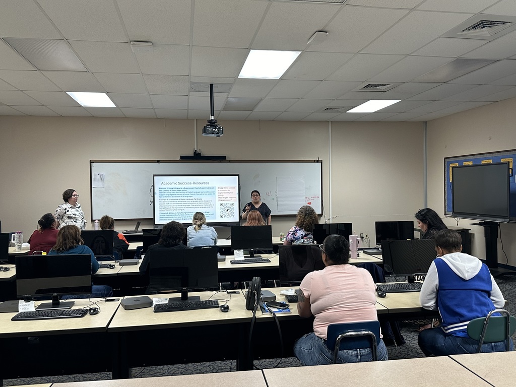 A classroom full of seated students facing a presentation on academic success resources, with computers and a projector visible.