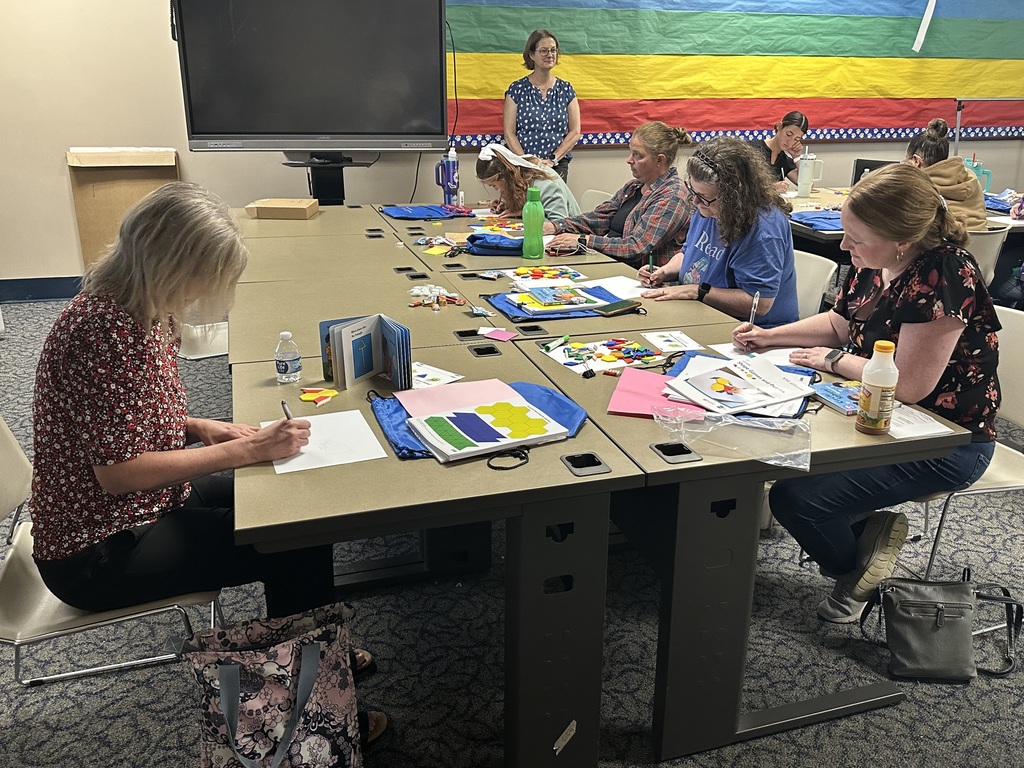 A group of women are engaged in a crafting workshop at a large table, surrounded by colorful supplies and materials.