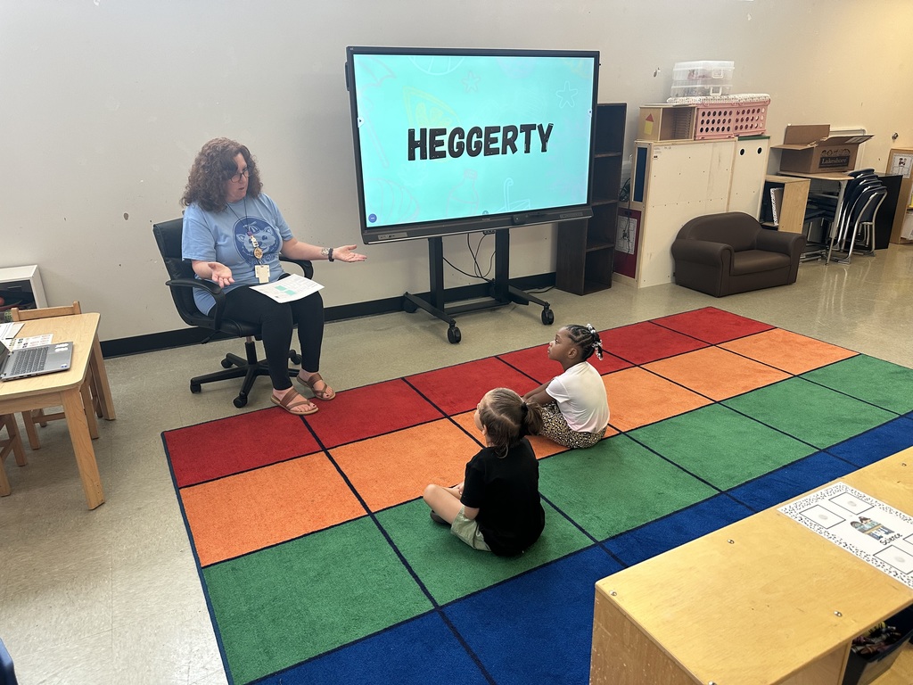 A teacher teaching two young students in a classroom.