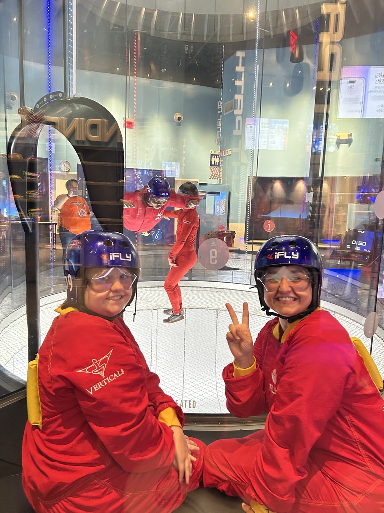 An adult and a student are taking a photo together. The adult is holding up the peace sign.