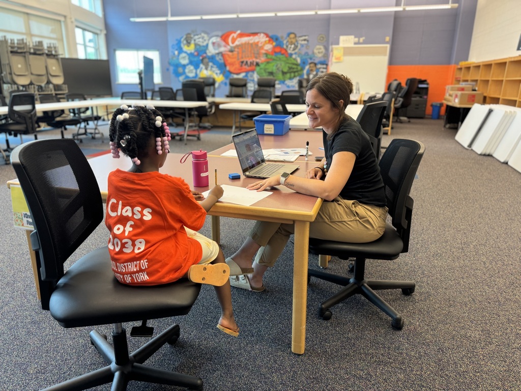 A teacher and an incoming Kindergarten student are working on a paper together during Ferguson Pre-8's recent Kindergarten Orientation event. The student is writing on the paper.