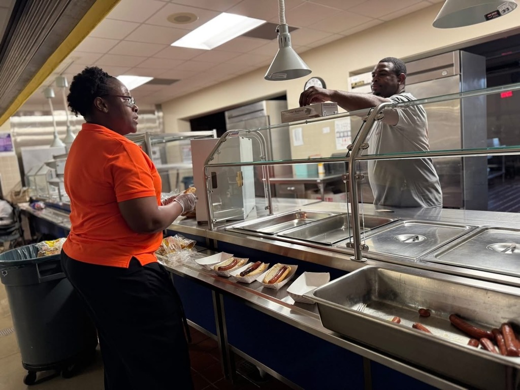 Devers Assistant Principal, Dr. Greene helping district staff member with hot dogs at Devers PreK-8's Back to School Night.