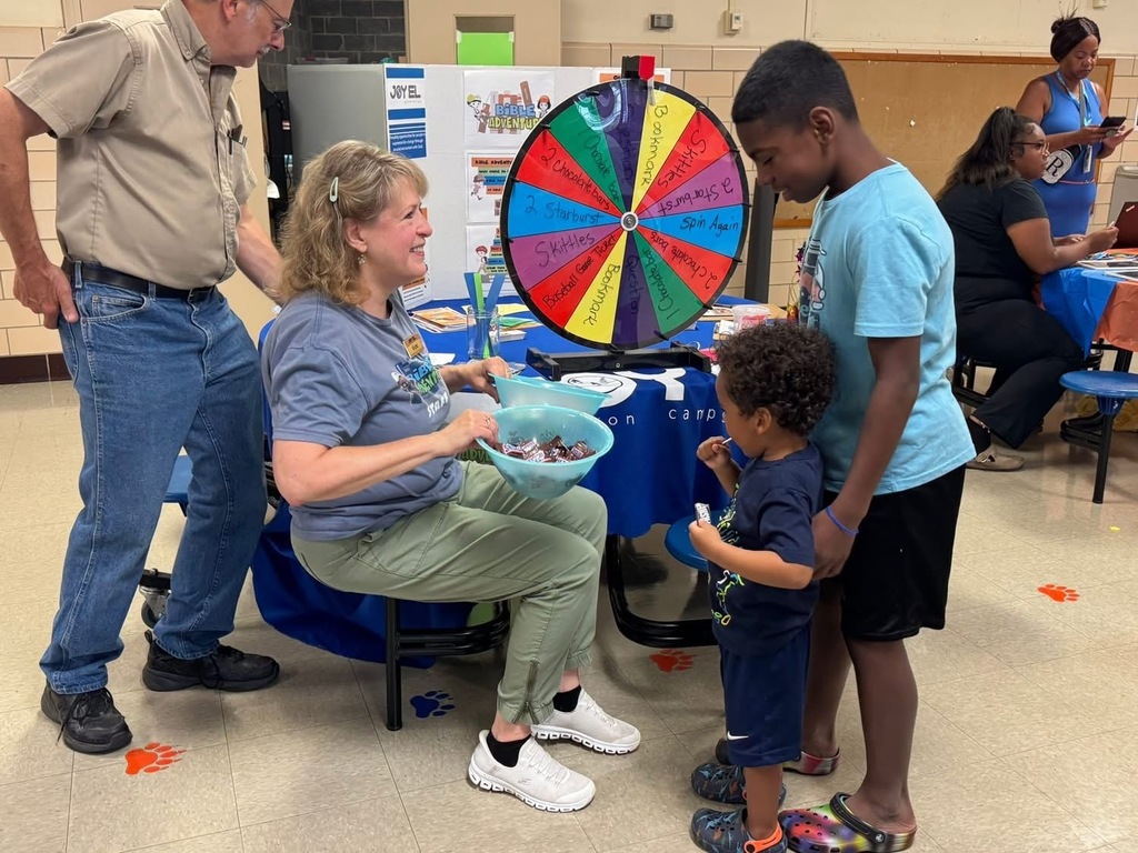 Two students looking down at a candy bowl held by a district staff member at Devers PreK-8's Back to School Night.