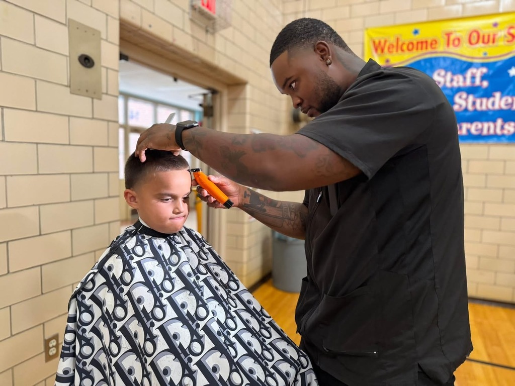 A barber cutting a young student's hair at Devers PreK-8's Back to School Night.