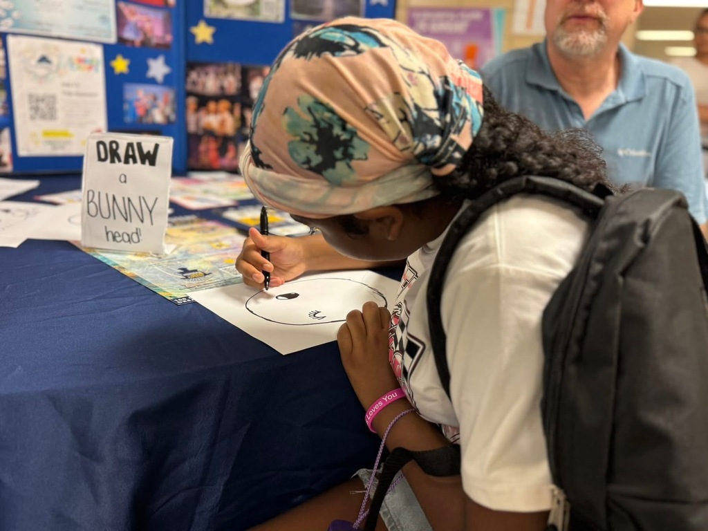 A student drawing a bunny head at Devers PreK-8's Back to School Night.