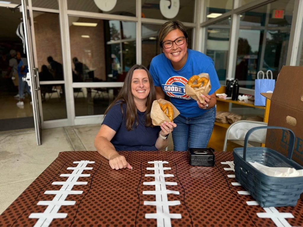 Two district staff members holding up pretzels at Goode PreK-8's Back to School Night.