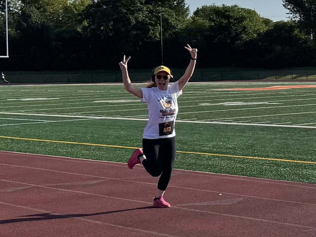 District staff member holding up peace signs in the middle of participating in the School District of the City of York's 5K Run and Walk.
