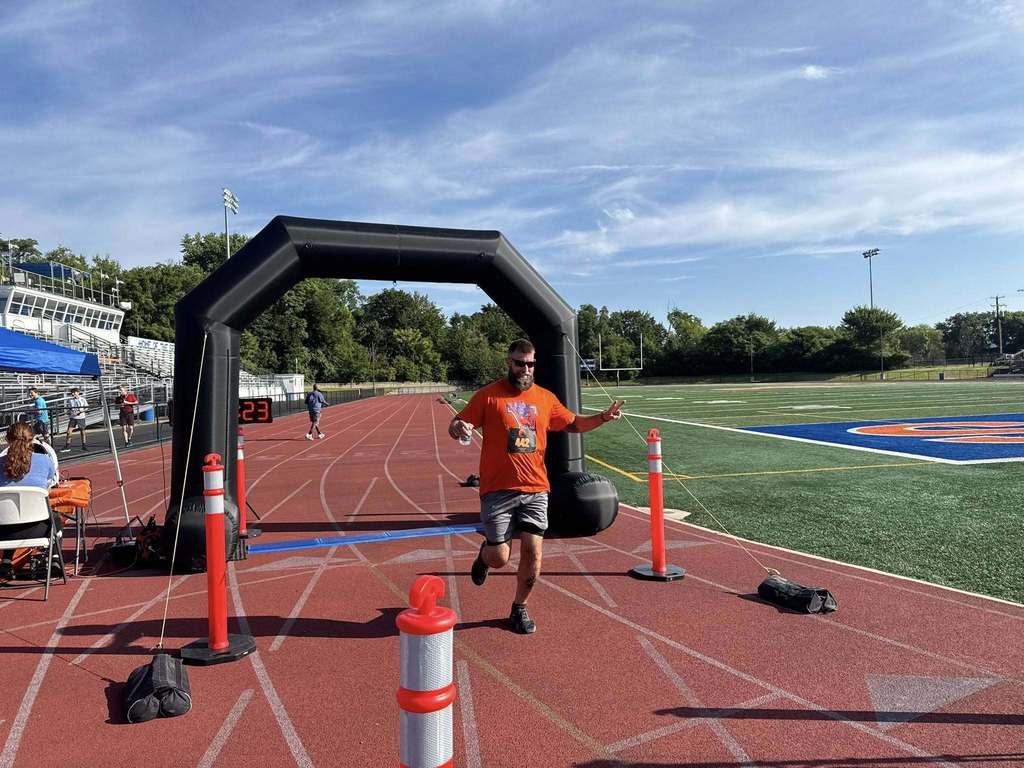 District staff member running past the finish line at the School District of the City of York's 3rd Annual Paws for Wellness 5K Run and Walk.