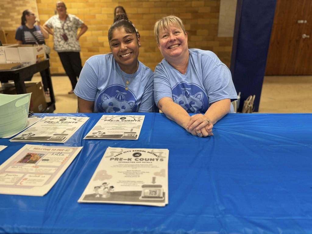 District staff members posing together at a table during Davis PreK-8's Back to School Night.