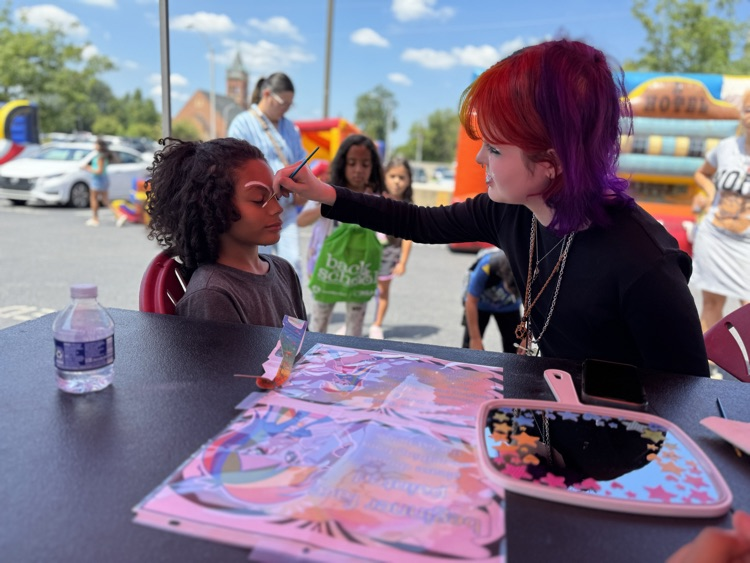 An adult painting a child’s face.