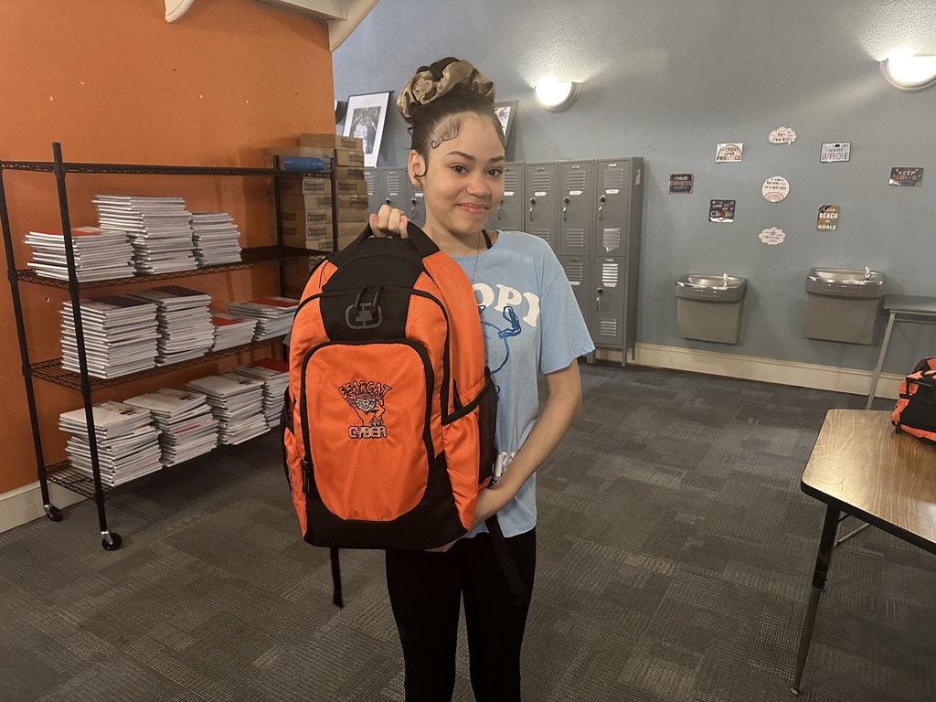 A Bearcat Cyber Academy student holding up a Bearcat Cyber Academy bookbag.