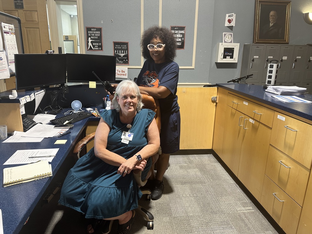 Two district staff members sitting and standing in the office area at Bearcat Cyber Academy.