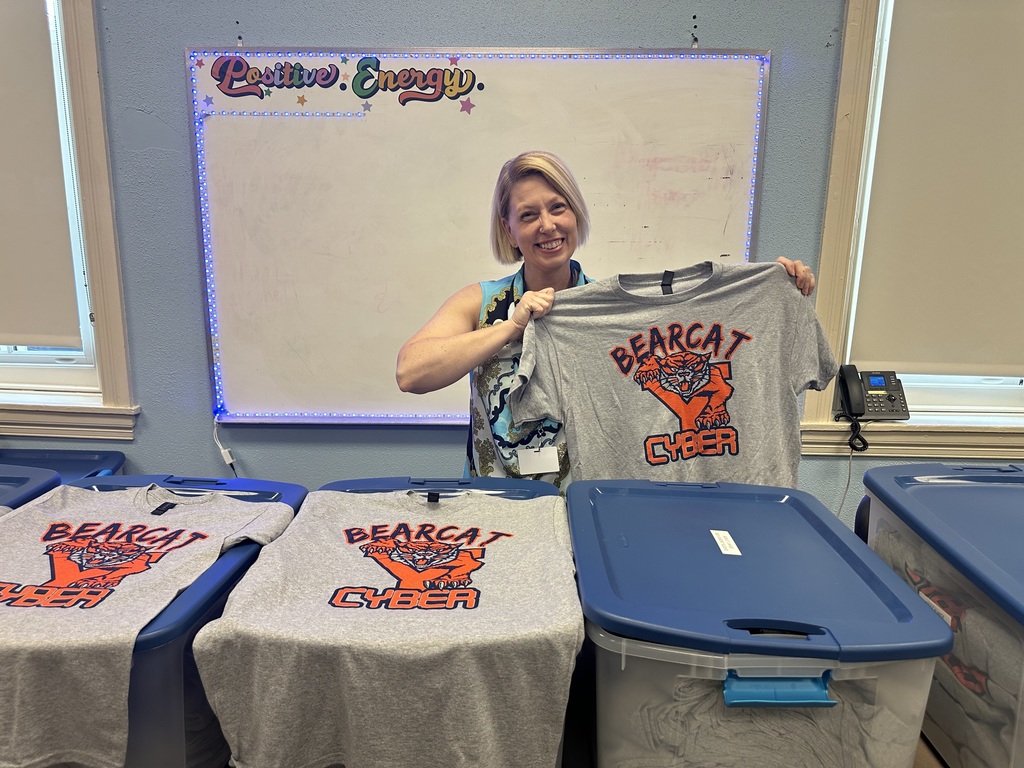 A district staff member holding up a shirt with the words "Bearcat Y Cyber" on it.