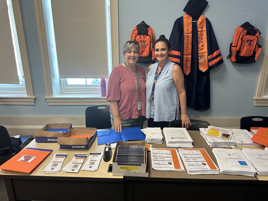 Two district staff members standing behind a table with papers and brochures on it.
