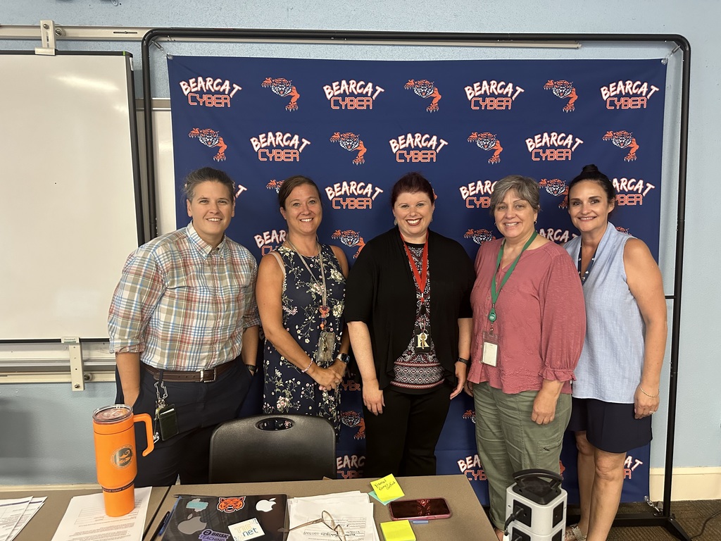 Five district staff members posing in front of a Bearcat Cyber backdrop.
