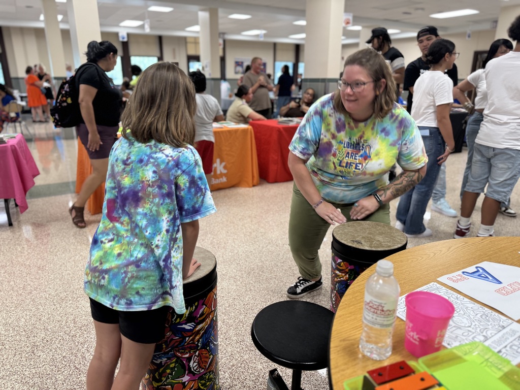 A district staff member and a student playing on an instrument.