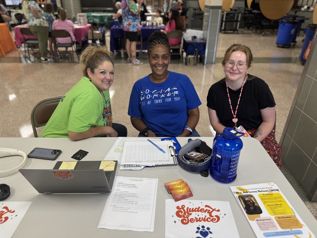 Three district staff members posing for a photo while sitting at a table. 