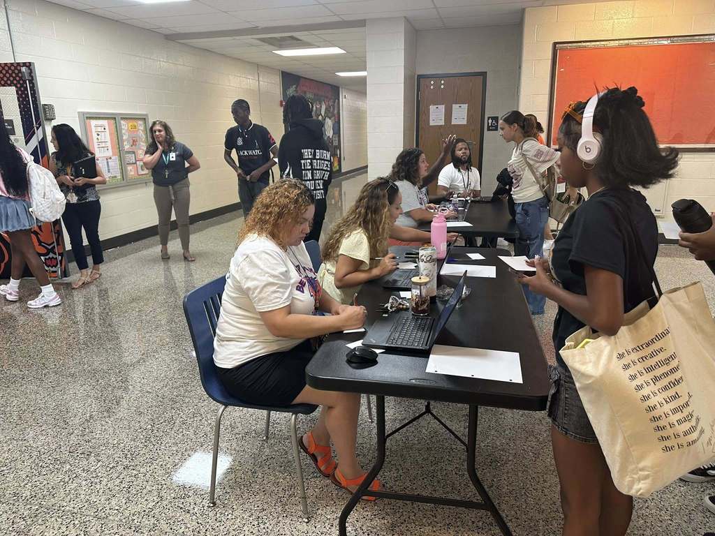 District staff sitting at tables helping students.