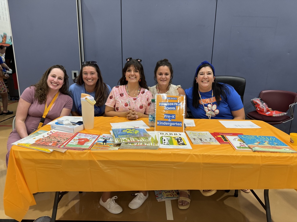 Five district staff members sitting at a table during Ferguson PreK-8's Back to School Night. 