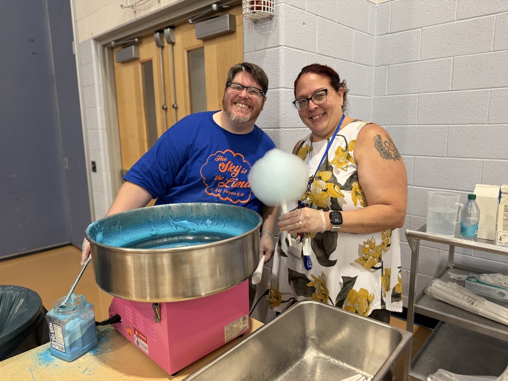 Two district staff members working at a cotton candy machine during Ferguson PreK-8's Back to School Night.