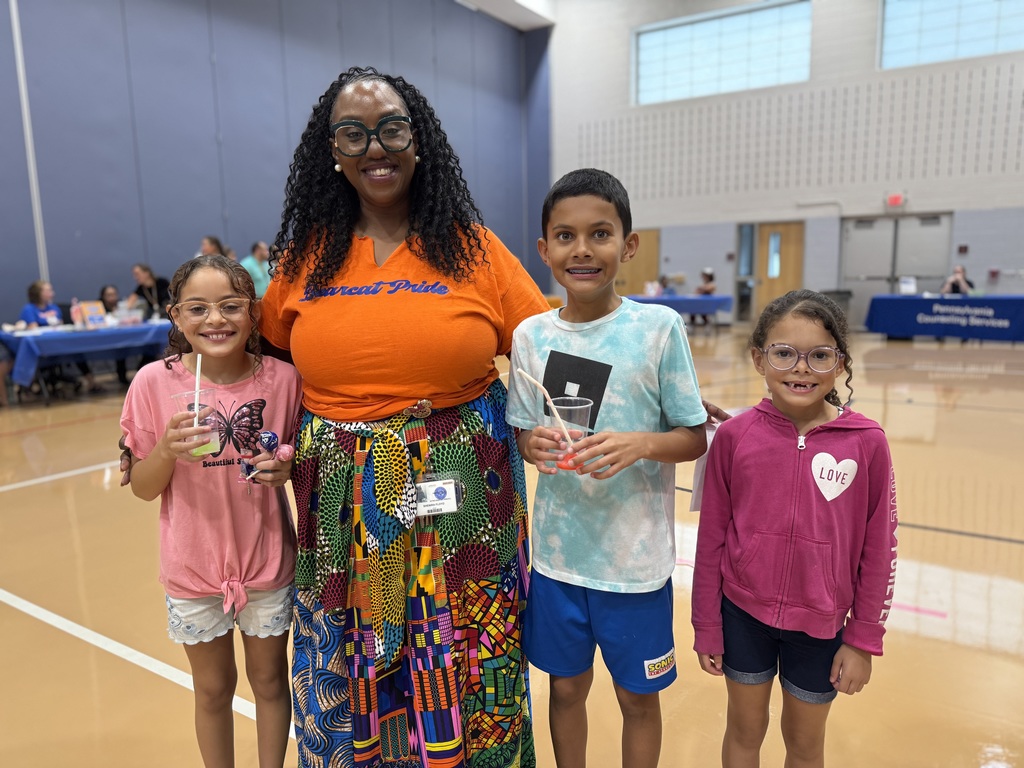 Ferguson PreK-8's Assistant Principal Floyd posing for a photo with three students during Ferguson PreK-8's Back to School Night. Two of the students are holding cups with a drink in it.