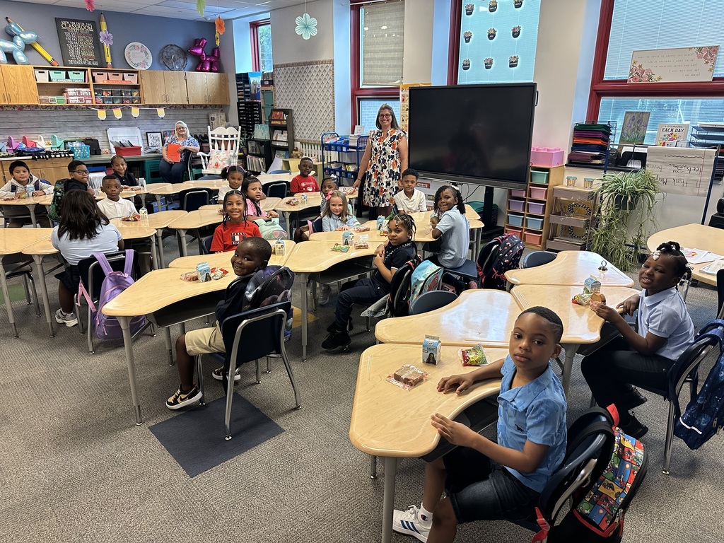 A teacher and a classroom of students looking at the camera for a photo.