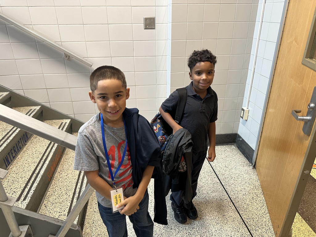 Two students at Hannah Penn PreK-8 posing for a photo near a staircase.